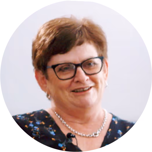 Smiling woman with glasses and short hair wearing a necklace.
