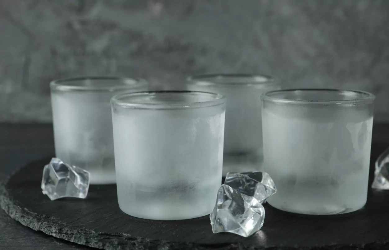 Ice shot glasses on black plate with ice cubes