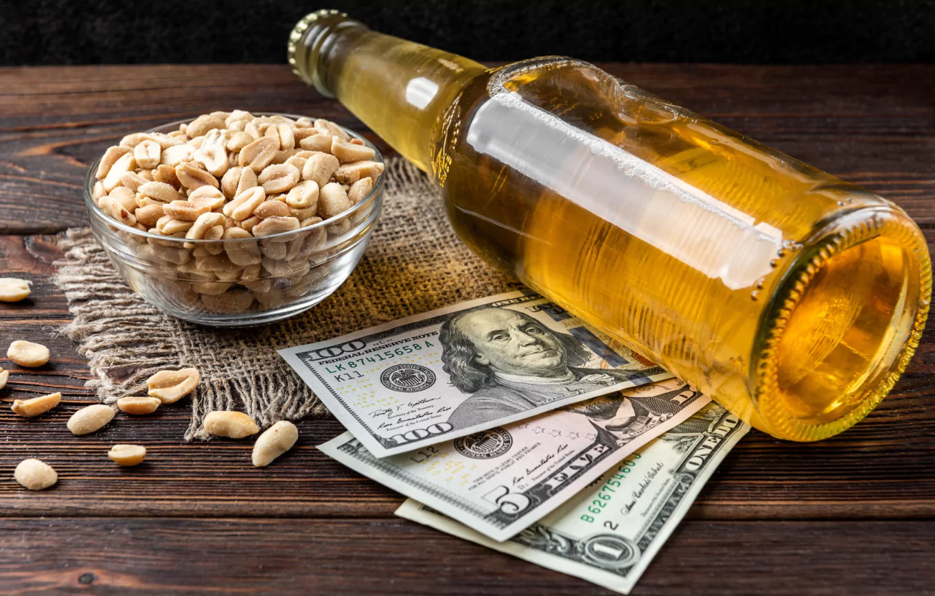 A jar of peanuts, a stack of money, and a bottle of alcohol