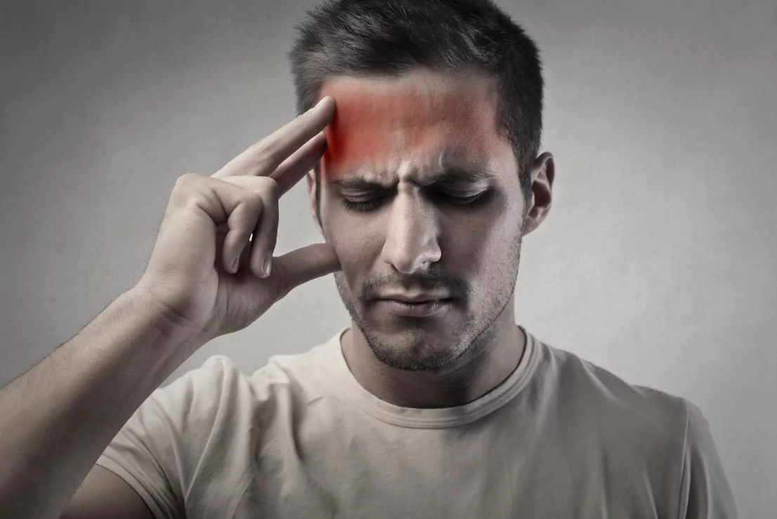 A man grimaces as he clutches his head