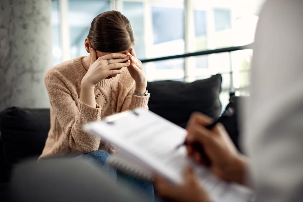 Woman sitting on couch with hands on head