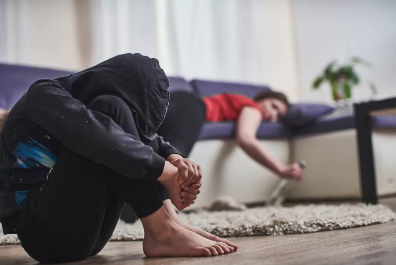 An alcoholic parent’s depressed child sitting on the floor