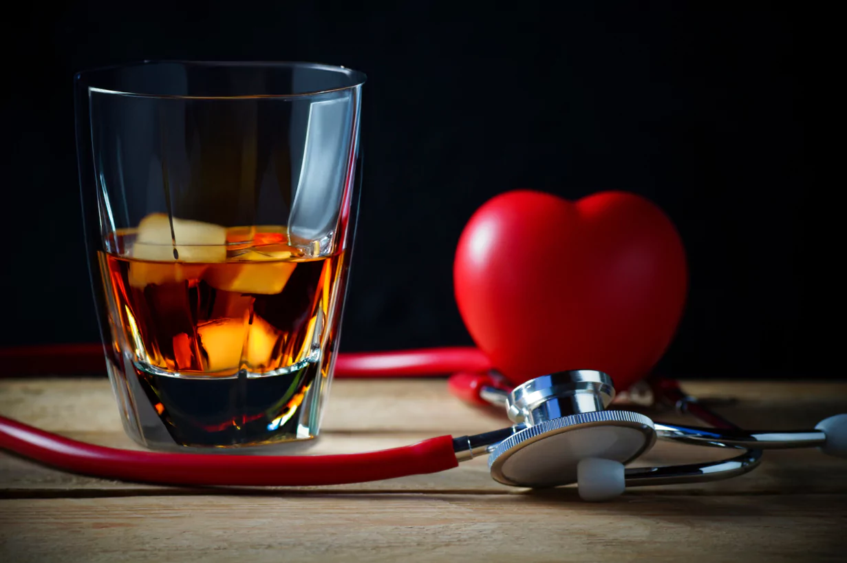 A glass of whiskey beside a heart-shaped stethoscope