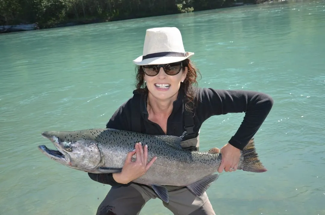 A woman holding up a salmon