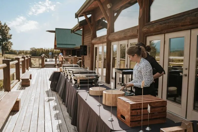 A wedding coordinator prepares a wedding buffet plate for the wedding couple on deck of Fraser River lodge