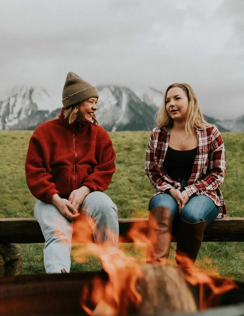 Two girls talk around a campfire