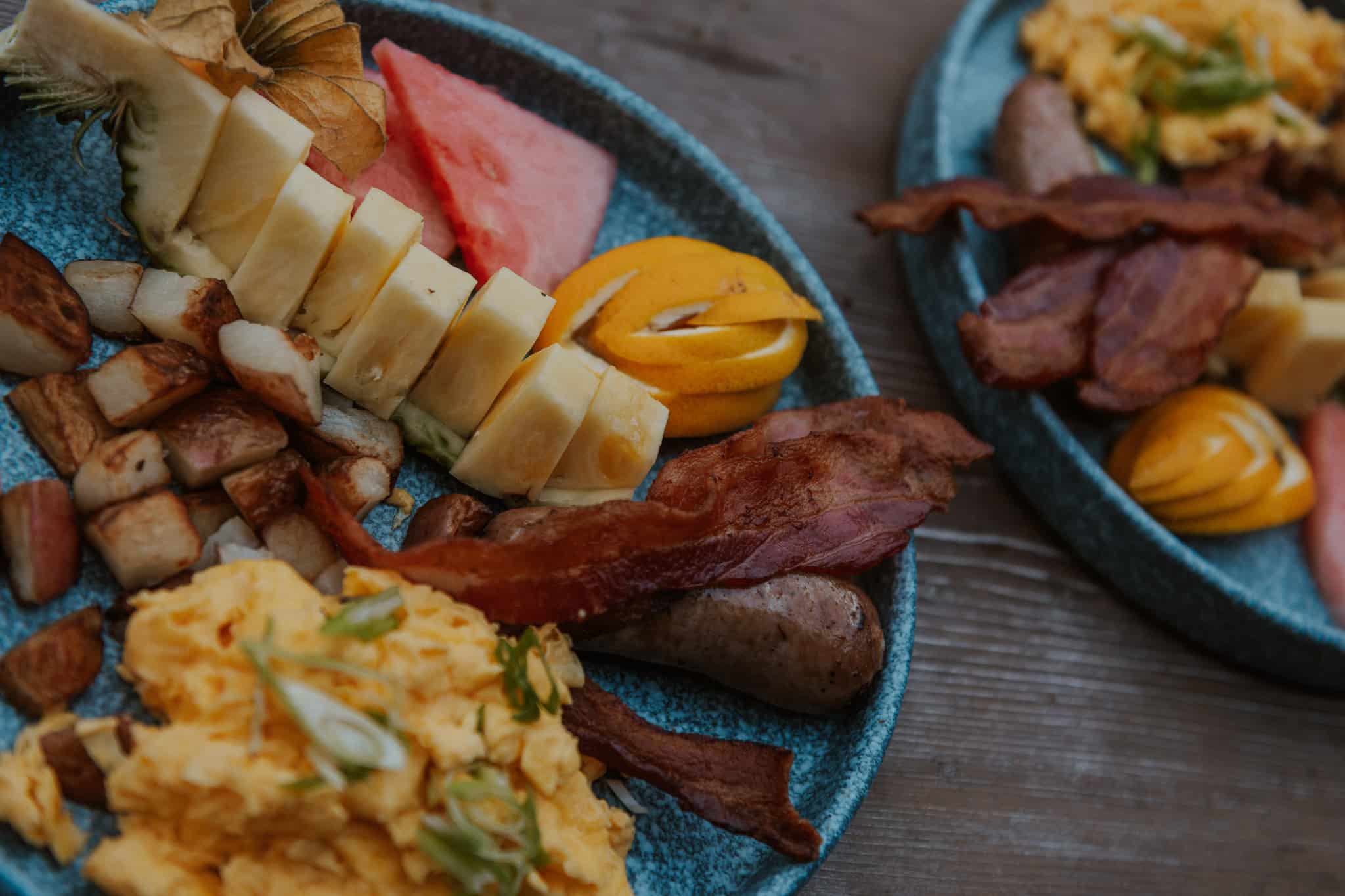 Two plates of a lodge breakfast with hashbrowns, eggs and bacon