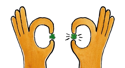 two hands holding clovers, one is a four leaf clover