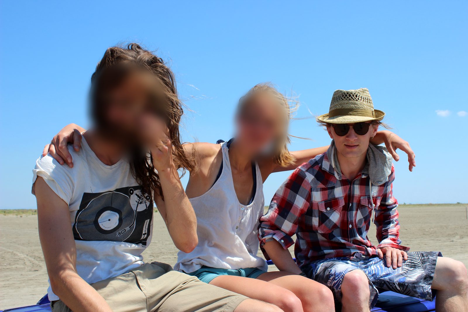Nikolai Voigt mit Strohhut und Sonnenbrille mit Freunden am Strand