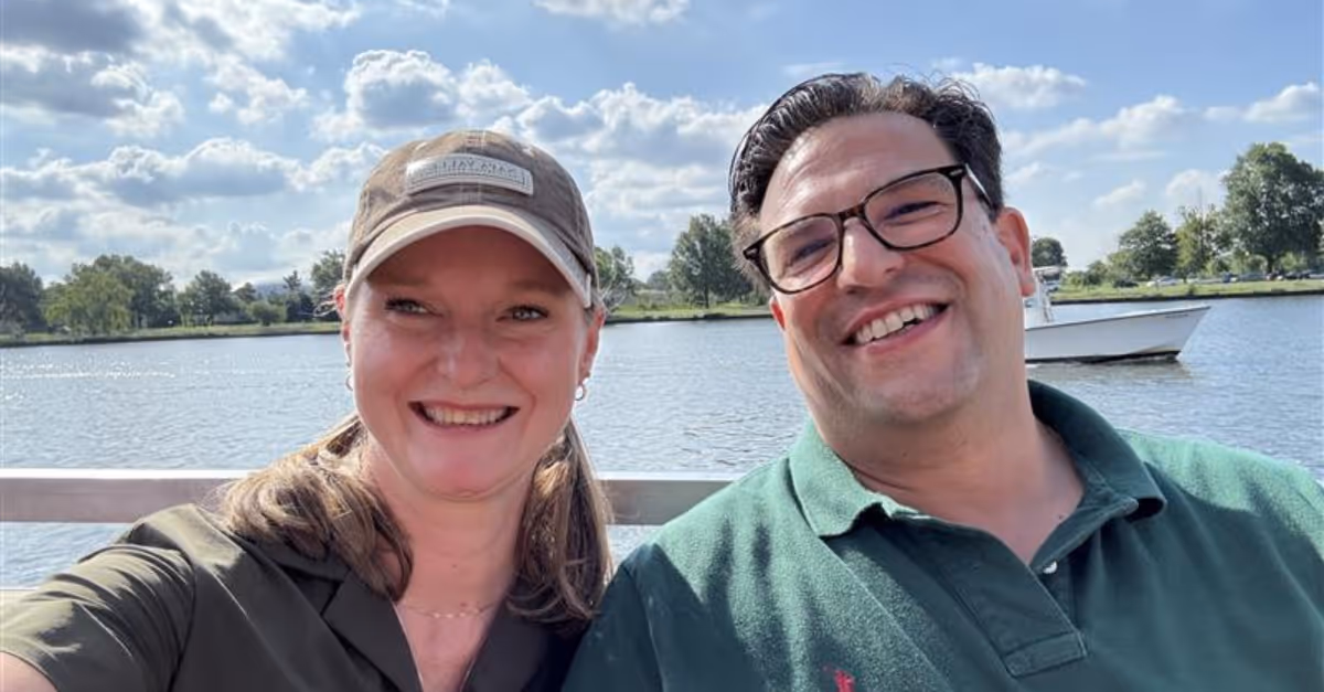 Two CoreView members taking a selfie in front of a lake with a boat