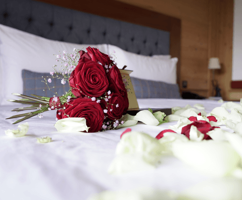 Photo of a bouquet of roses and wedding carnations on a bed in one of the rooms at Chalet RoyAlp Hôtel & Spa,