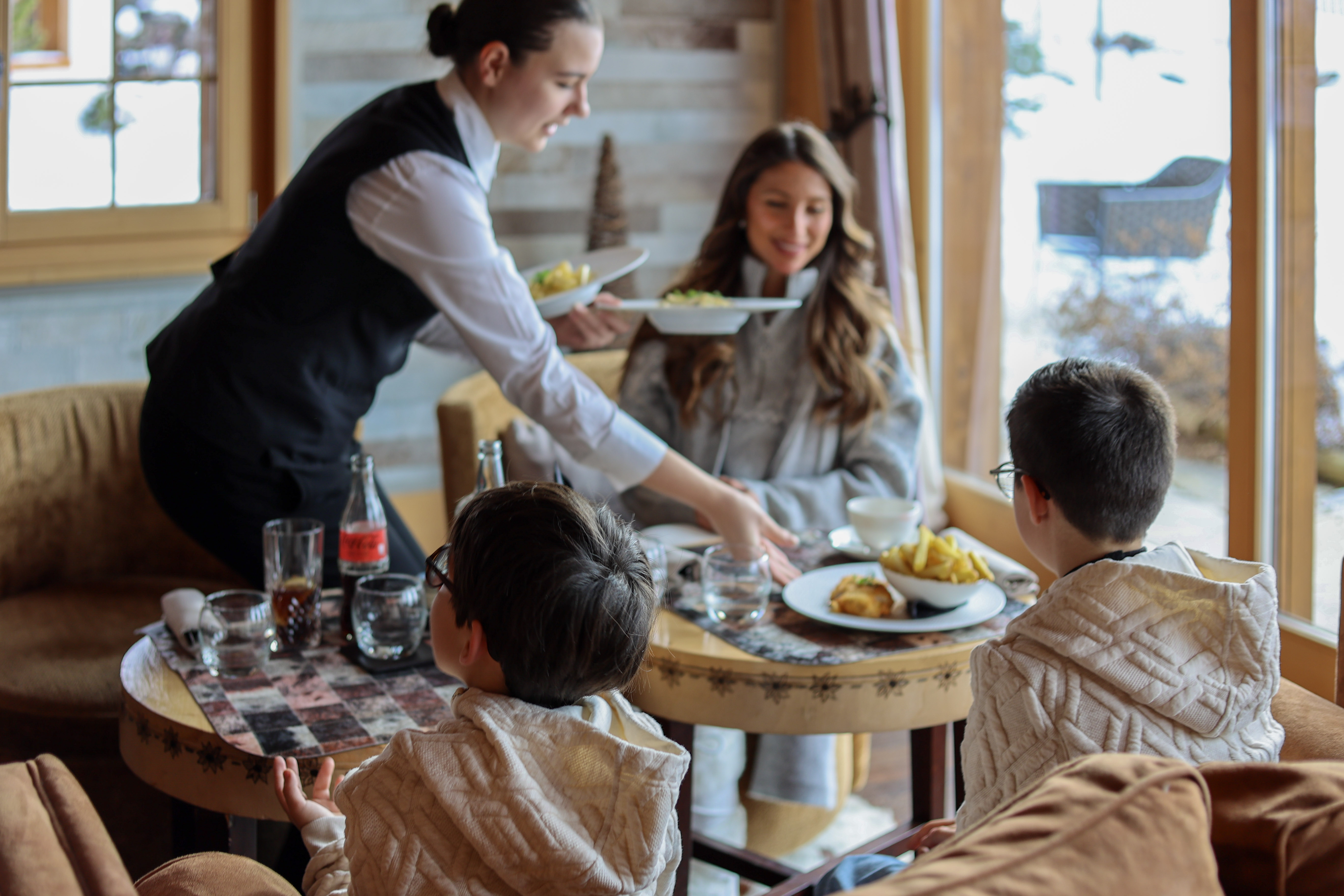 Family watching a film while being served popcorn inside the Chalet RoyAlp Hôtel & Spa cinema.