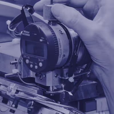 Hand adjusting a Mitutoyo digital micrometer measuring precision metal parts.