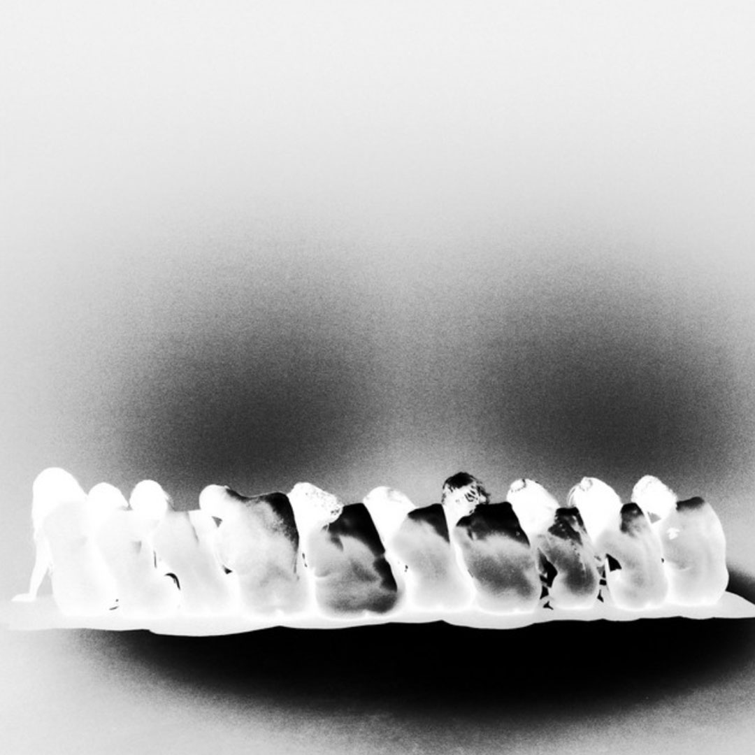 Negative filter image of a row of sushi pieces on a plate against a plain background.