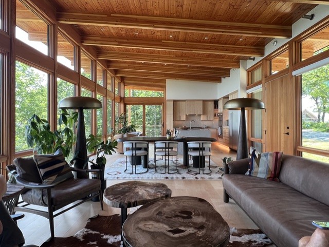A modern mountain home with exposed wood beams and a wood ceiling and a floor to ceiling glass wall.