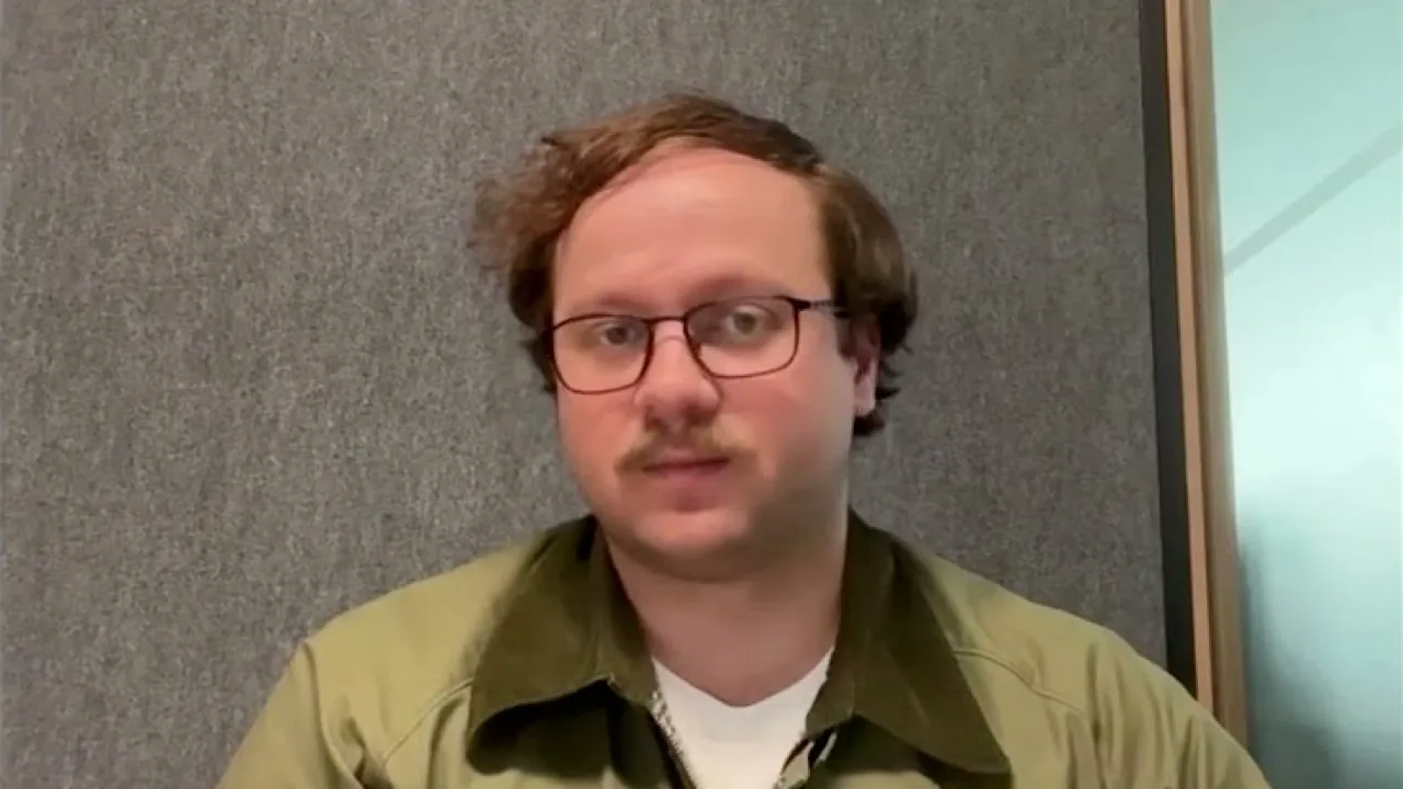 A person speaking to the camera in a video call, standing in for the IT director in this example