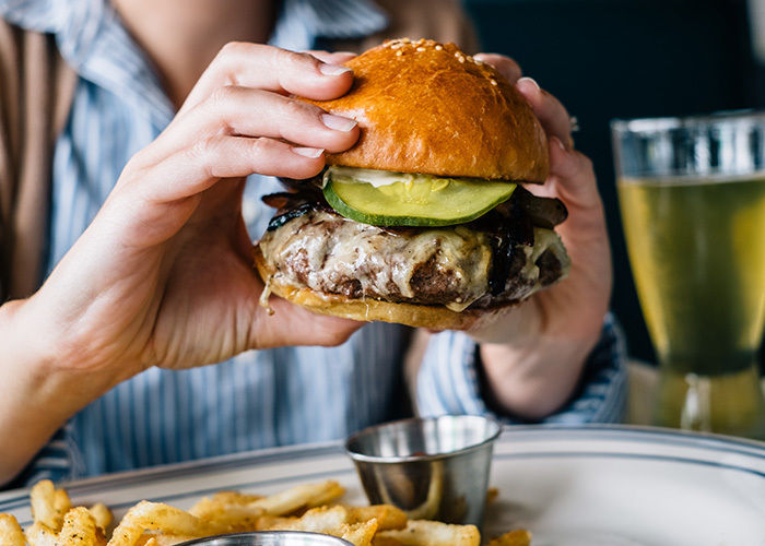 Juicy cheeseburger with pickle on golden bun, served with french fries
