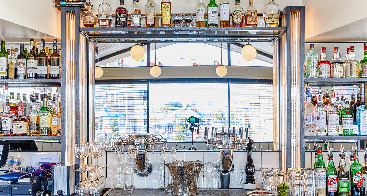 Well-stocked bar with various liquor bottles, glasses, and modern lighting