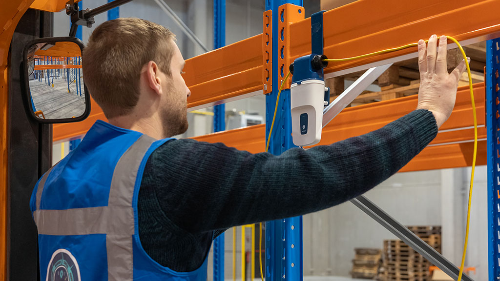 Een Pozyx Enterprise Anchor wordt aan een magazijnrek bevestigd.