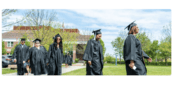 Graduates in robes walk together smiling 