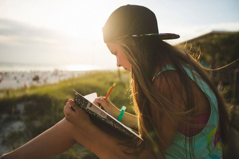 A student journaling during quiet time near the beach at BigStuf in 2014