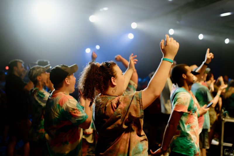 Students raising their hands during a BigStuf auditorium worship session in 2021