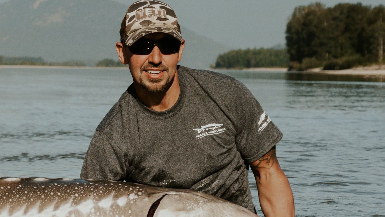 A fishing guide holding a sturgeon in the river