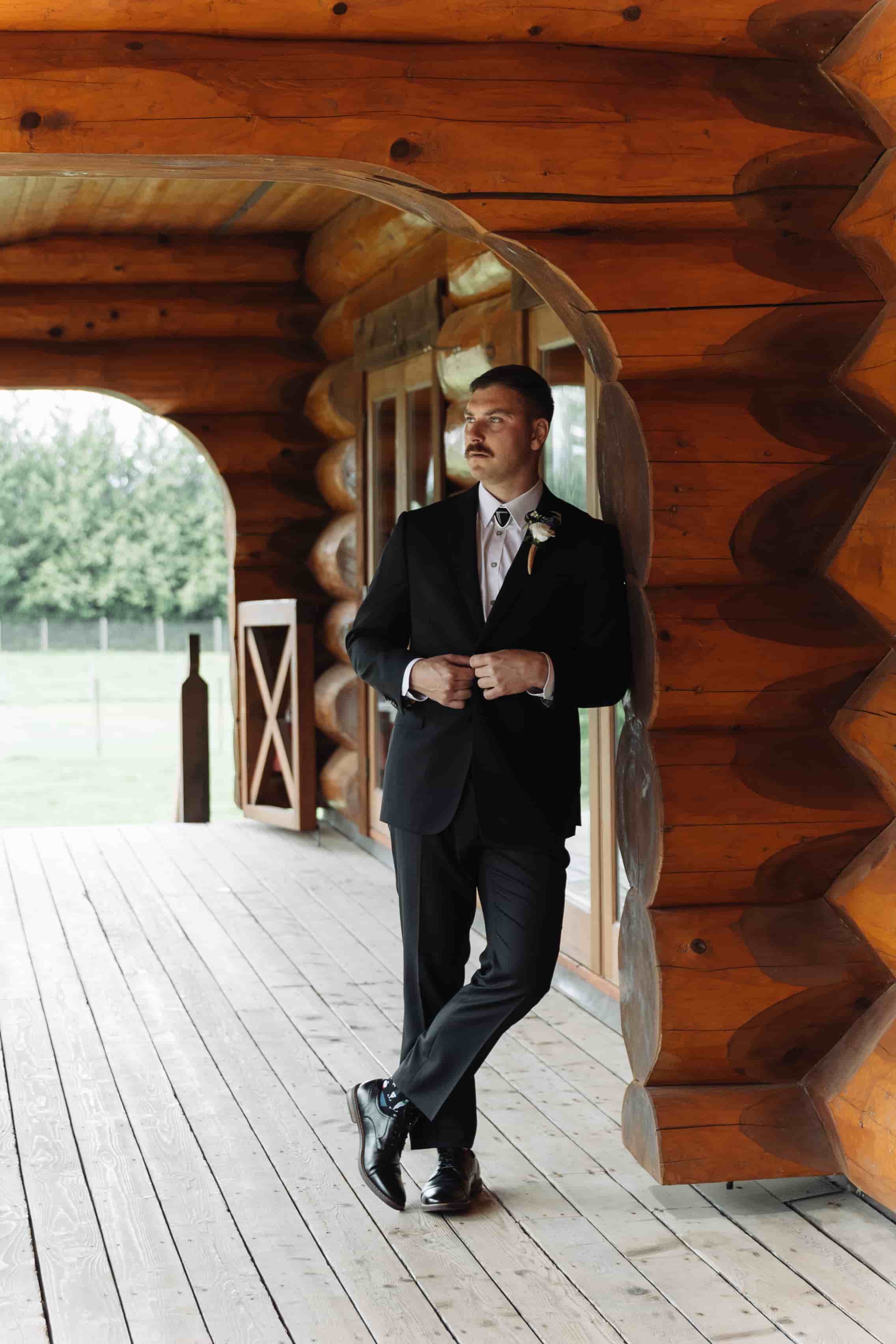 A groom leaning against the Fraser River Lodge