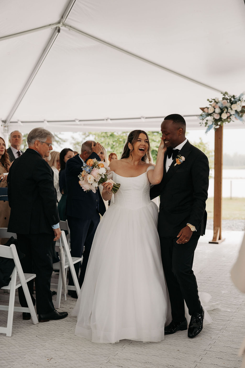 A bride and groom walking back down the aisle after getting married in a tent at the fraser river lodge