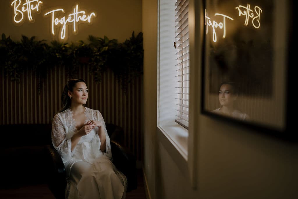 A bride getting bridal portraits down in the wedding suite, her reflection visible in a picture frame