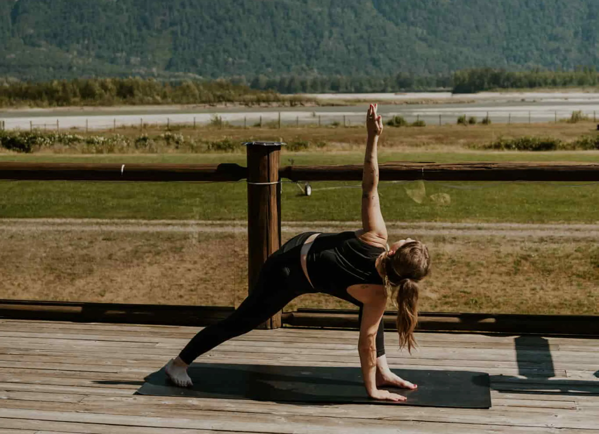 A yoga instructor at the Fraser River Lodge instructing yoga outside on the deck with mountain views in the background
