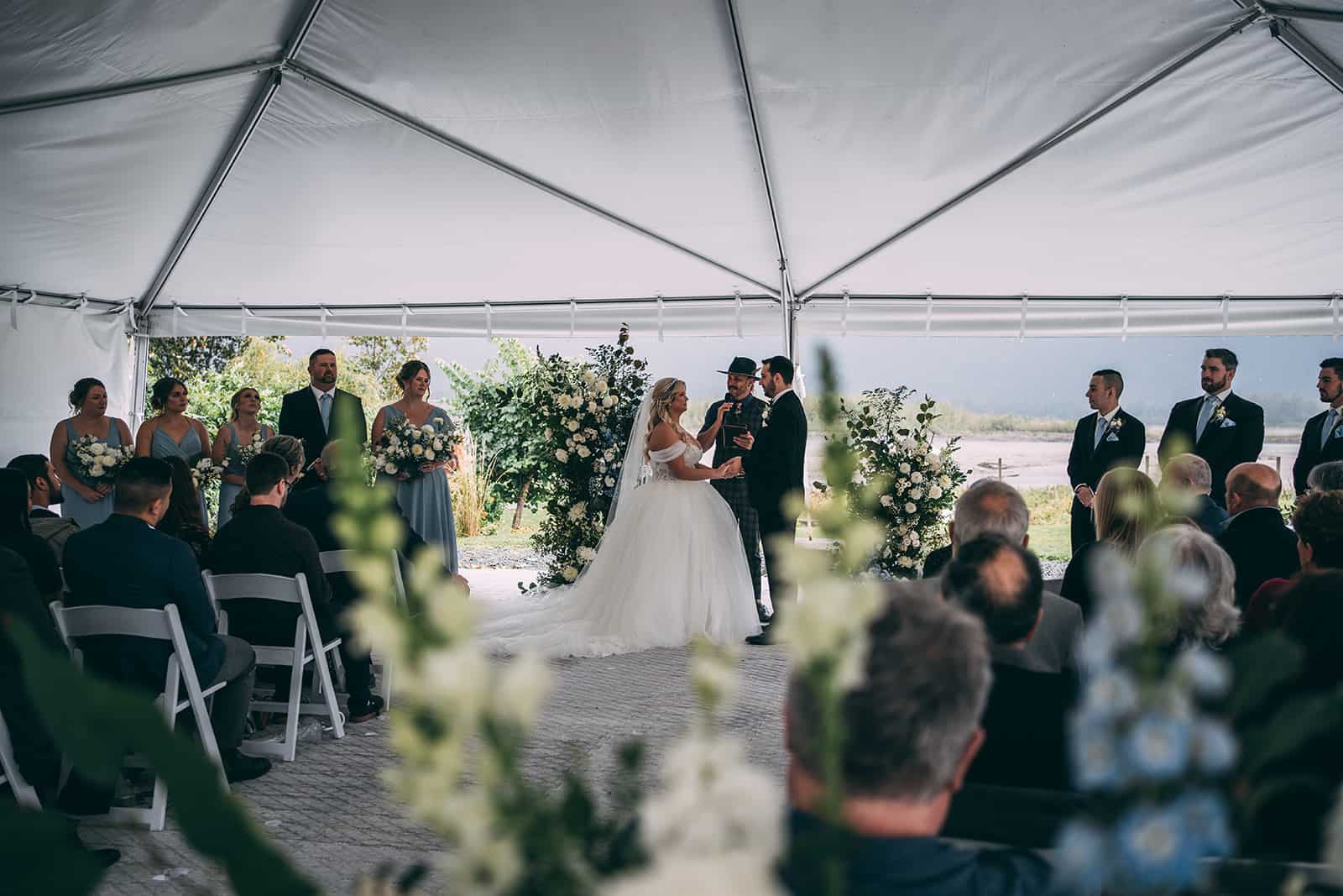 A wedding couple getting married outside under a tent