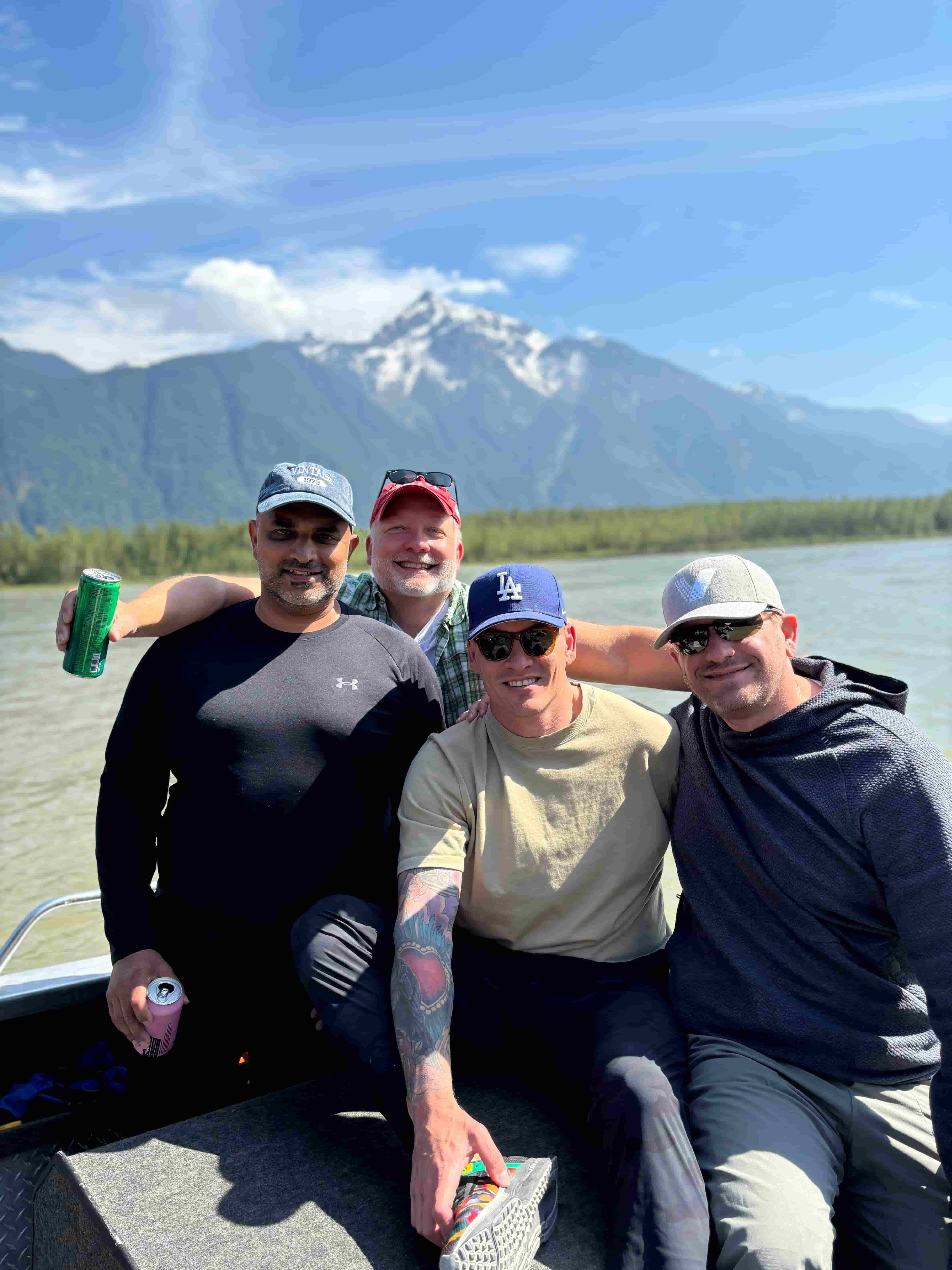 group of men posing in front of the mountains in a boat on the river