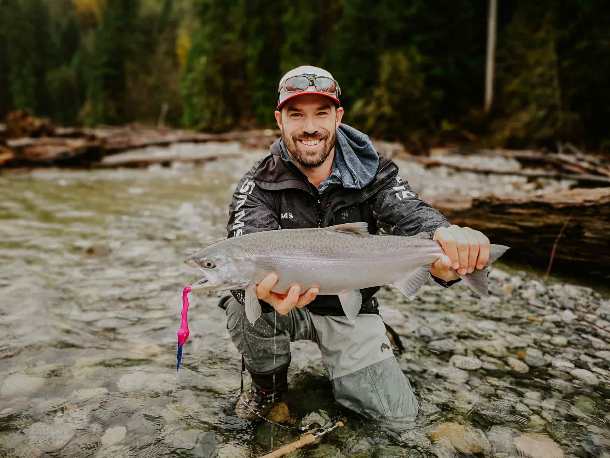 A man holding up his coho salmon catch on a wilderness river