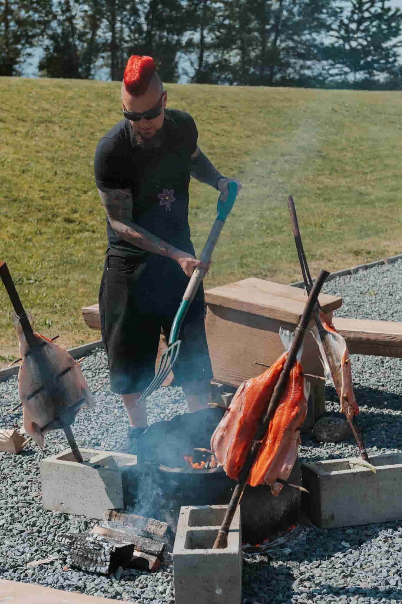 An indigenous man cooking salmon over an open fire