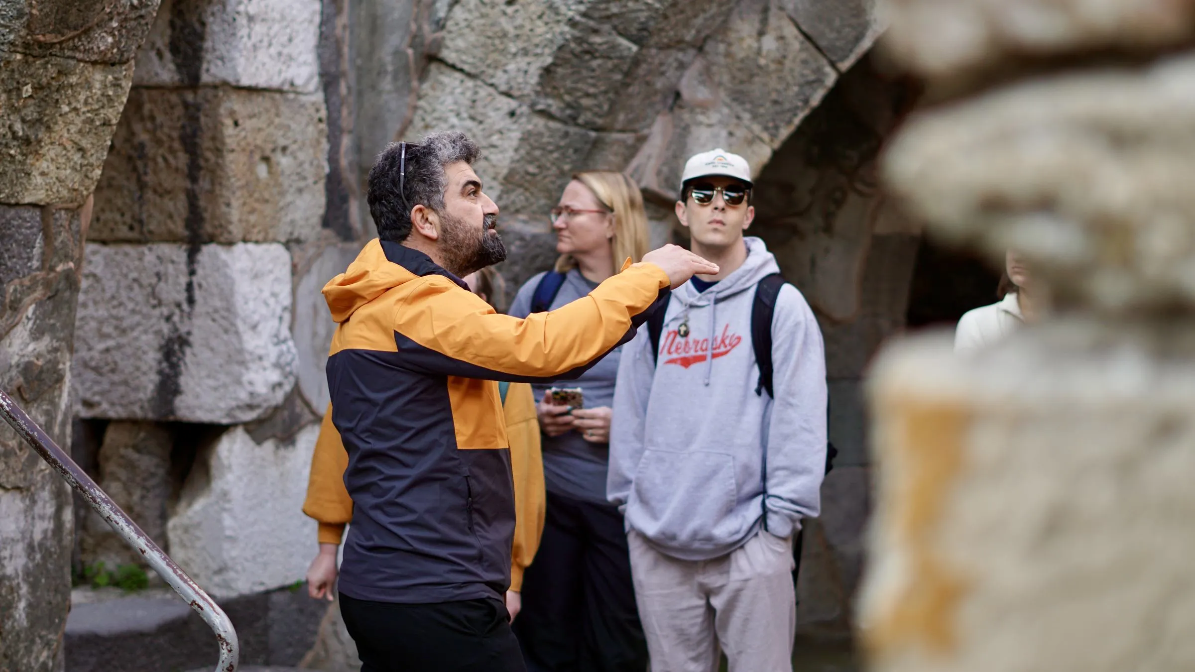 Guide Metin pointing out a detail to travelers beside the stone arches of the agora in Smyrna