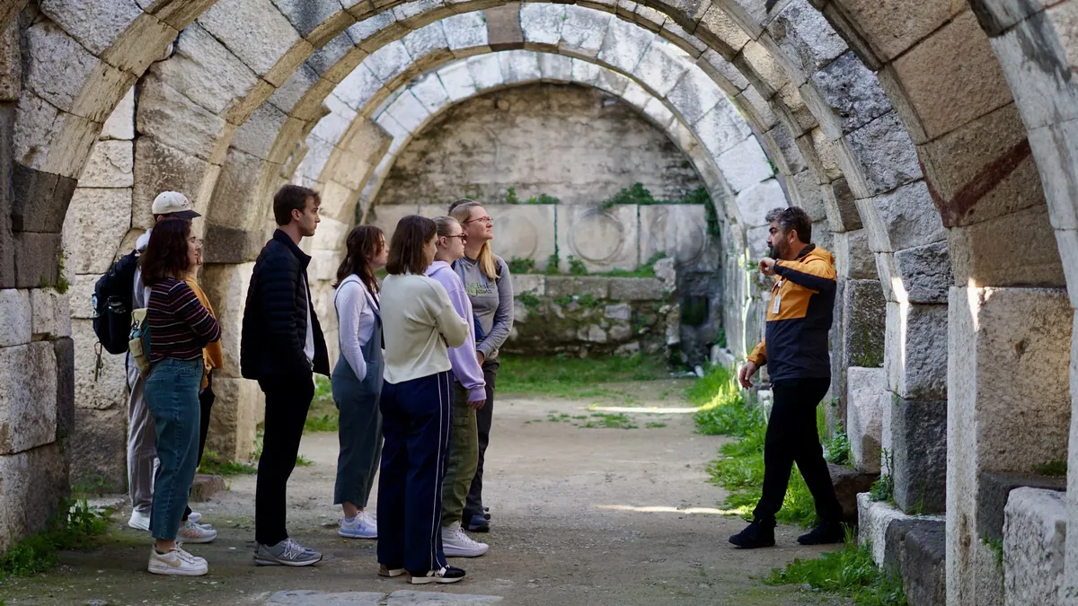 Guide Metin pointing out a carving to an Enjoy Tours group beneath the Roman arches of the agora in Smyrna