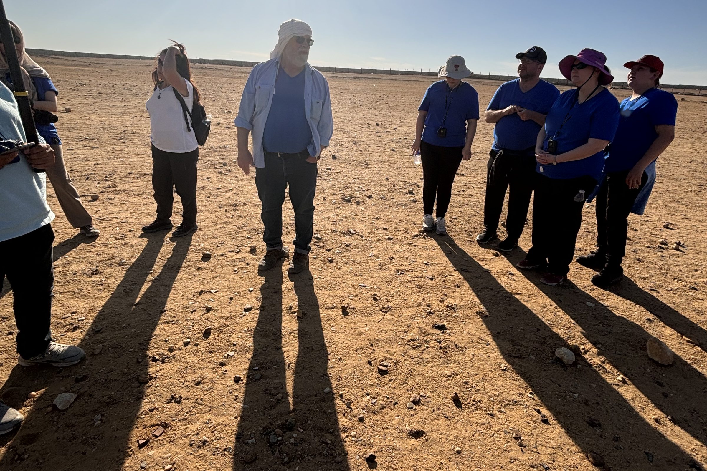 A group crossing the desert near the pyramids.