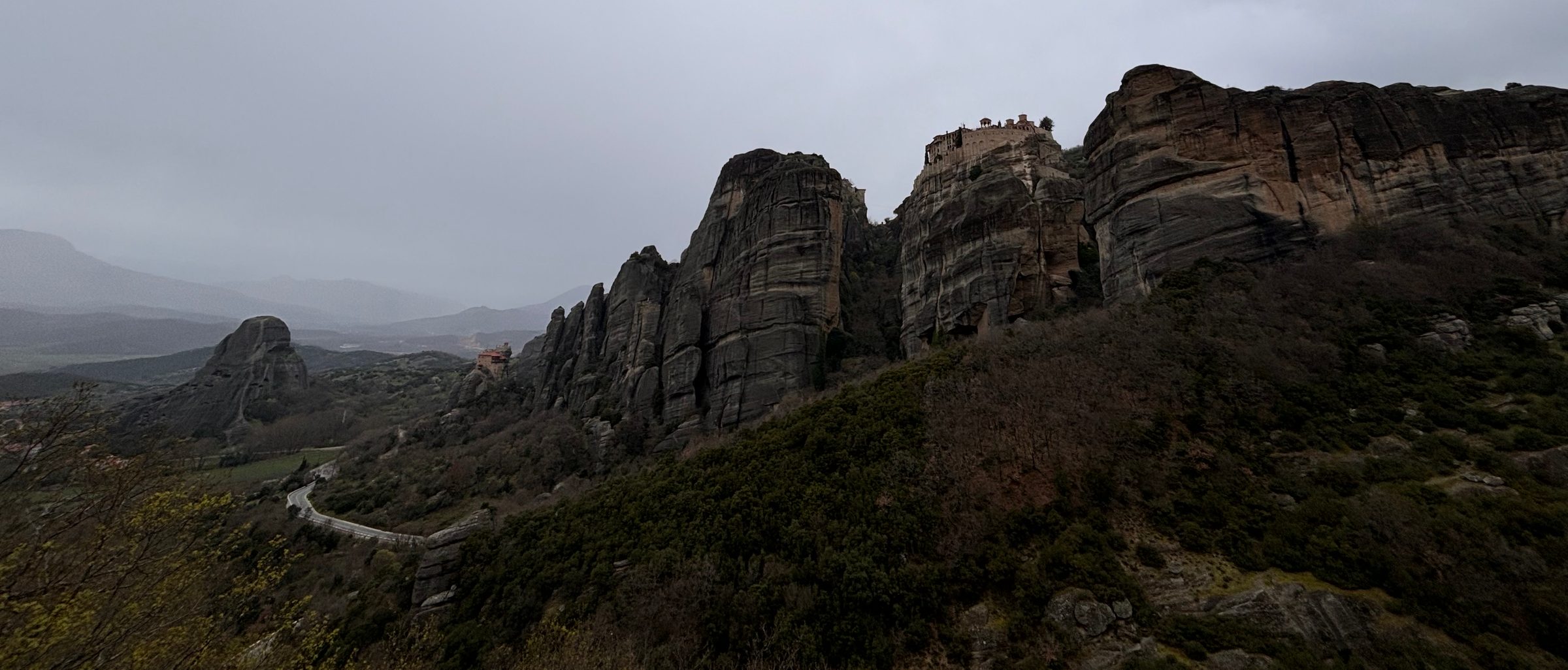 The sandstone pillars of Meteora under a grey sky.