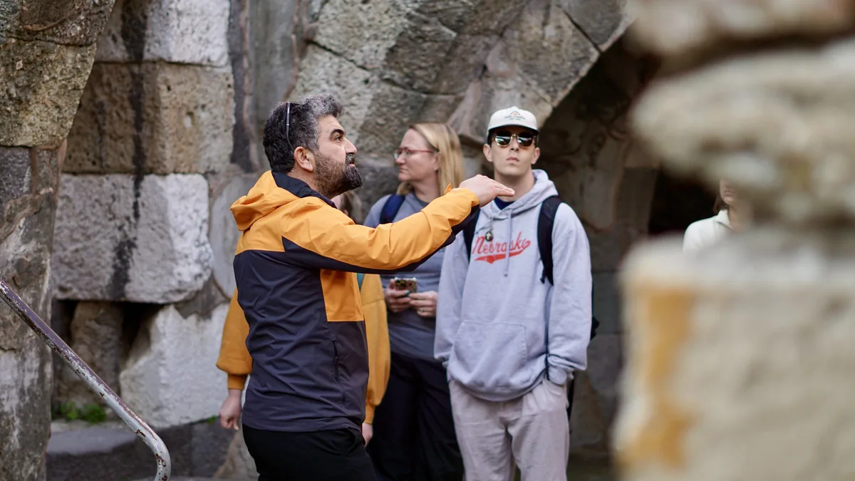 Guide Metin pointing out a detail to travelers beside the stone arches of the ancient agora in Smyrna