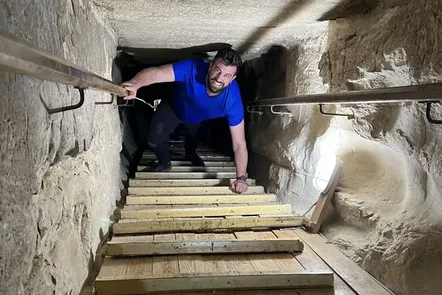 Climbing out of the narrow passage inside a pyramid in Egypt.