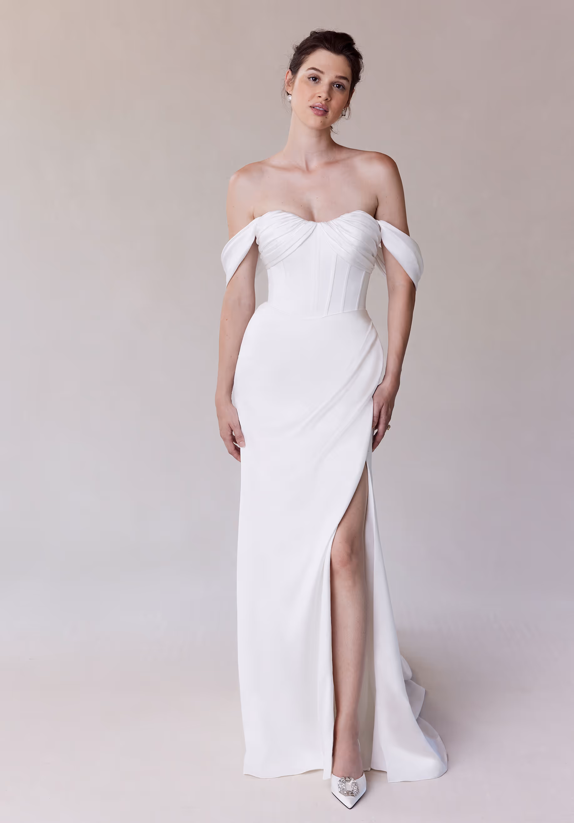 Elegant sheath wedding dress has corset boned bodice with a draped sweetheart neckline and detachable off-the-shoulder sleeves on a draped stretch satin skirt.