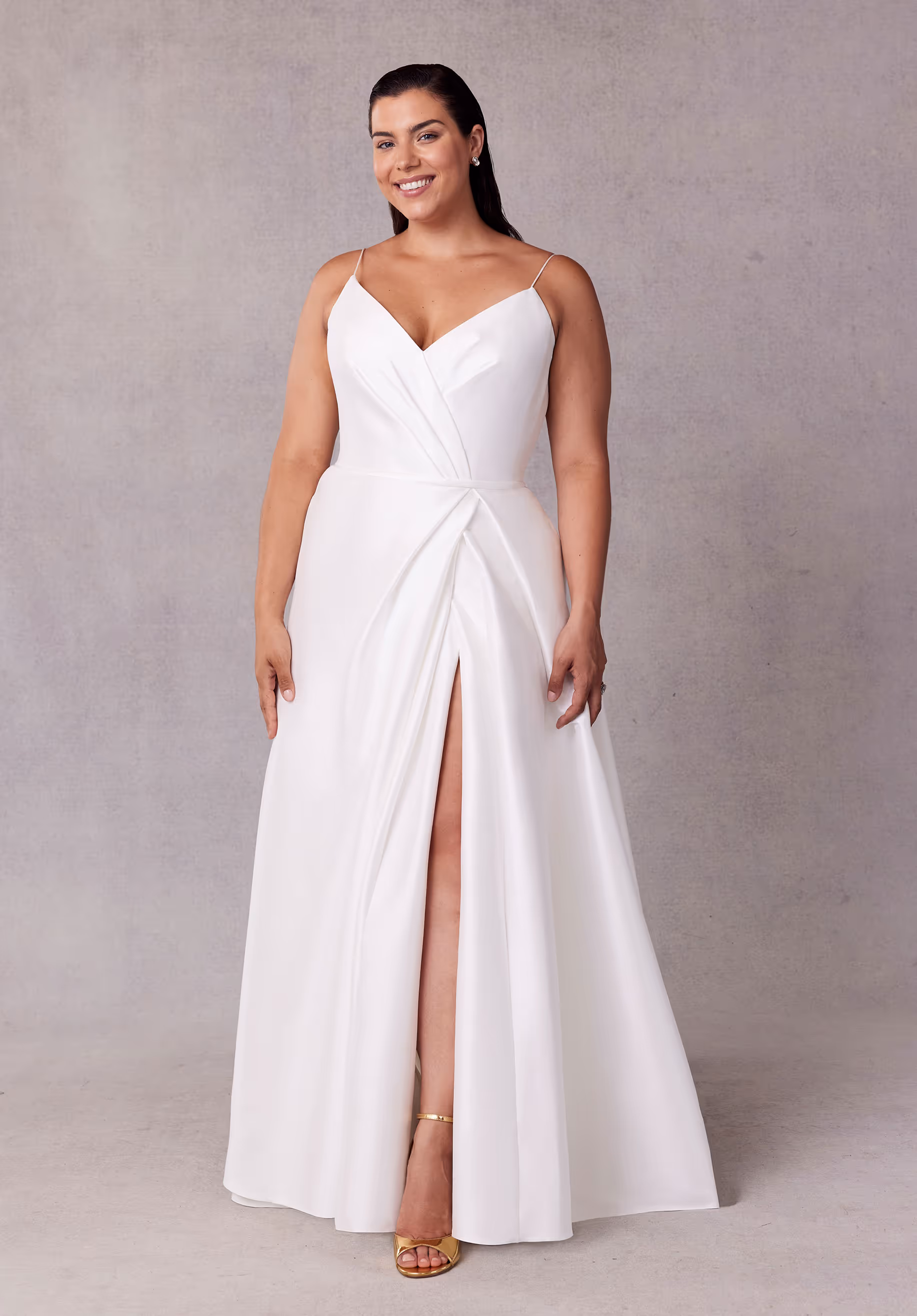 Elegant A-line wedding dress has a draped, surplice bodice with delicate straps, a waistband, and draped skirt slit in stretch Larissa satin.