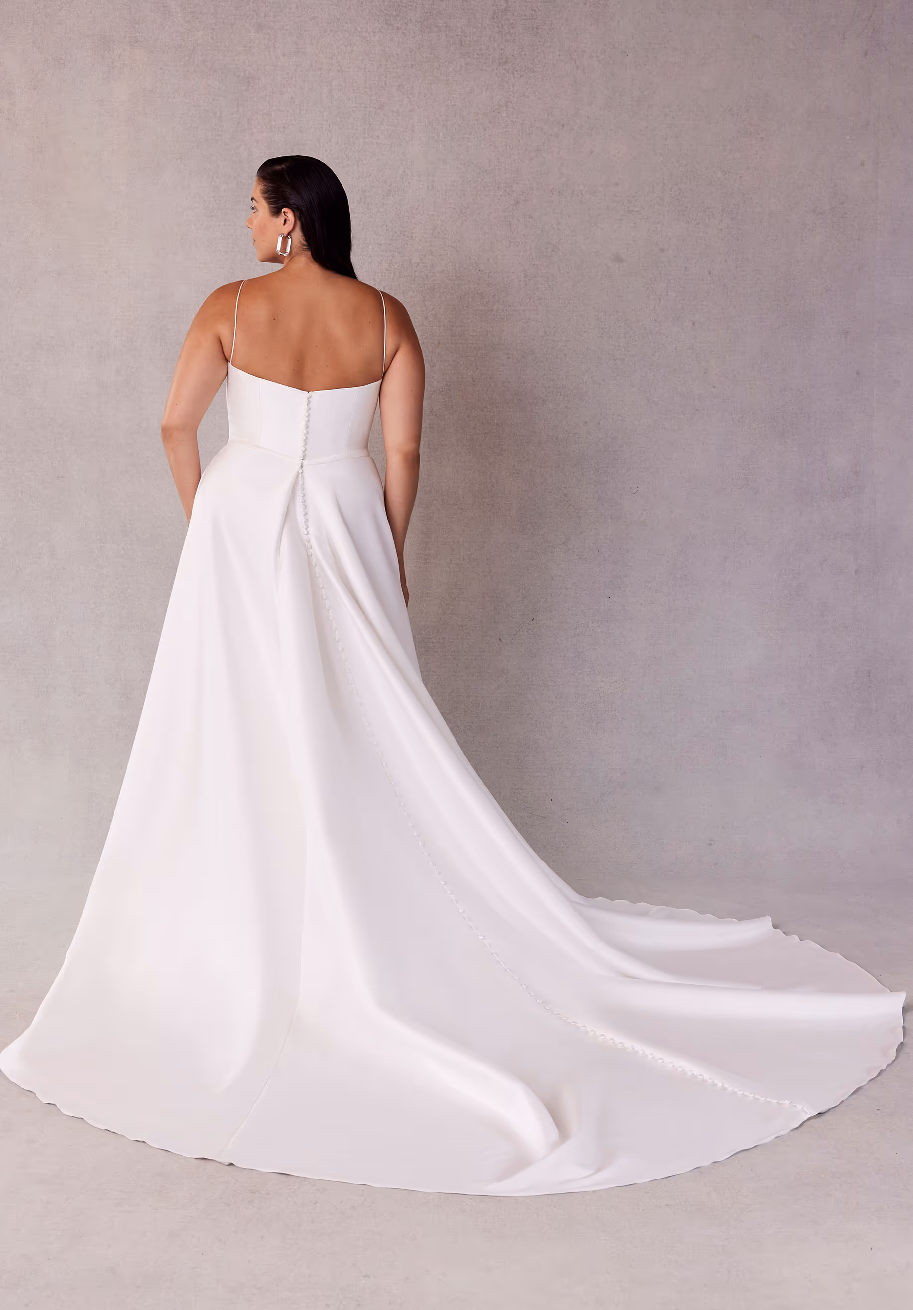 Elegant A-line wedding dress has a draped, surplice bodice with delicate straps, a waistband, and draped skirt slit in stretch Larissa satin.