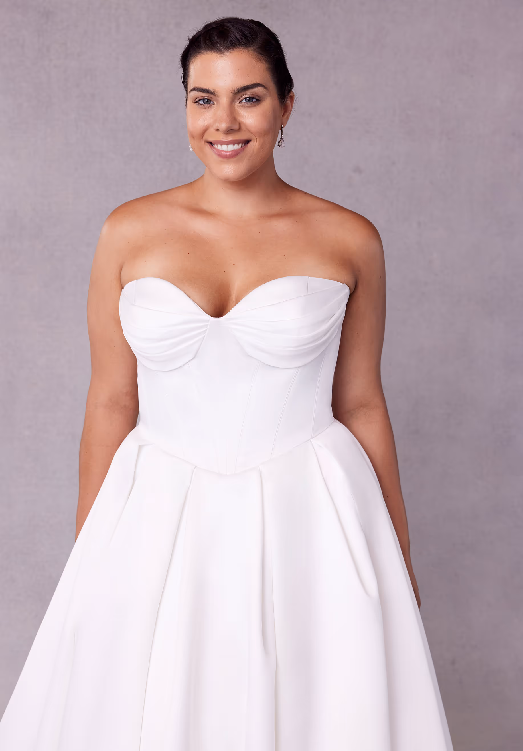 Timeless ball gown wedding dress has a sweetheart corset bodice with beaded, draped bust on a basque waist with lace-up corset back, detachable off-the-shoulder sleeves, and side bustles on a box-pleated satin skirt.