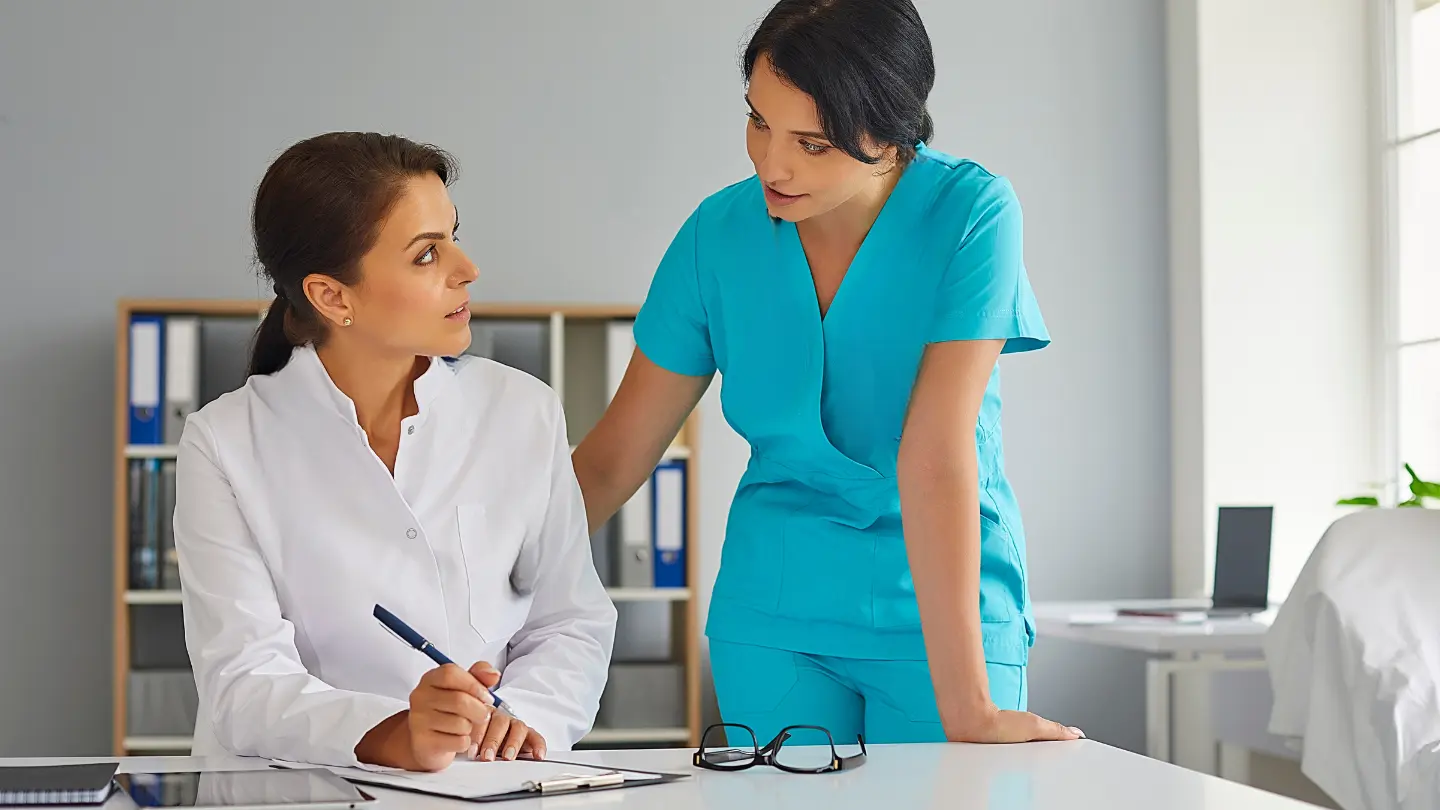 Medical aesthetics staff training in a UK clinic. Senior practitioner mentoring a new team member during a development session. Ideal for showcasing investment in staff development and patient care excellence in aesthetic practices.