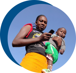 A woman holding a baby and a phone looking at the camera
