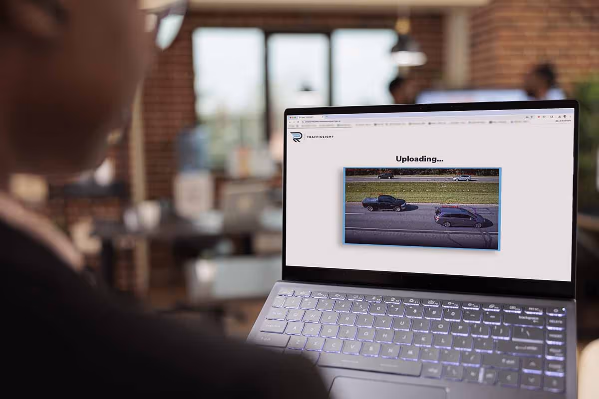 Man looking at laptop while uploading a video of traffic footage