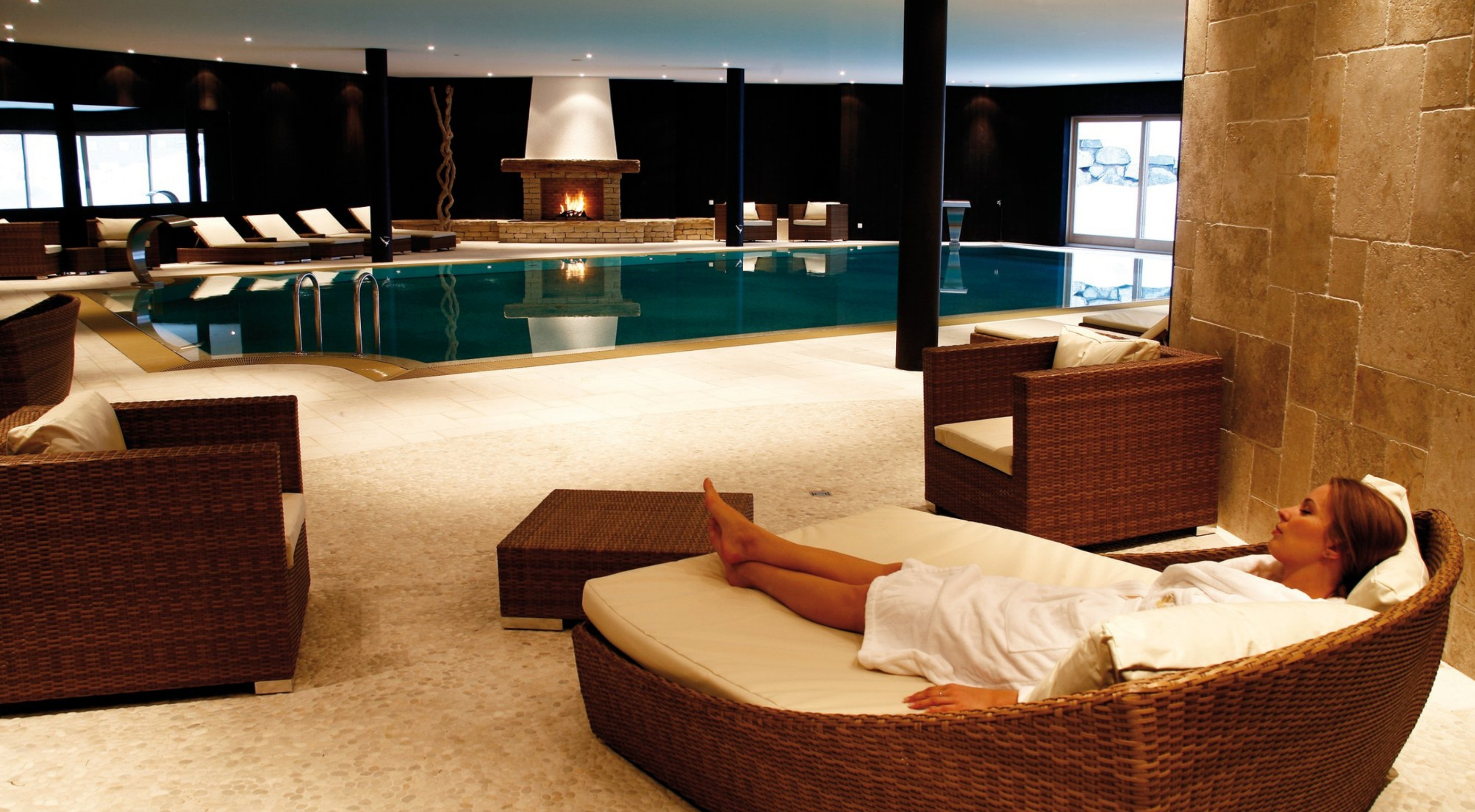 Inside the Chalet RoyAlp spa, a person relaxes in a comfortable deckchair.