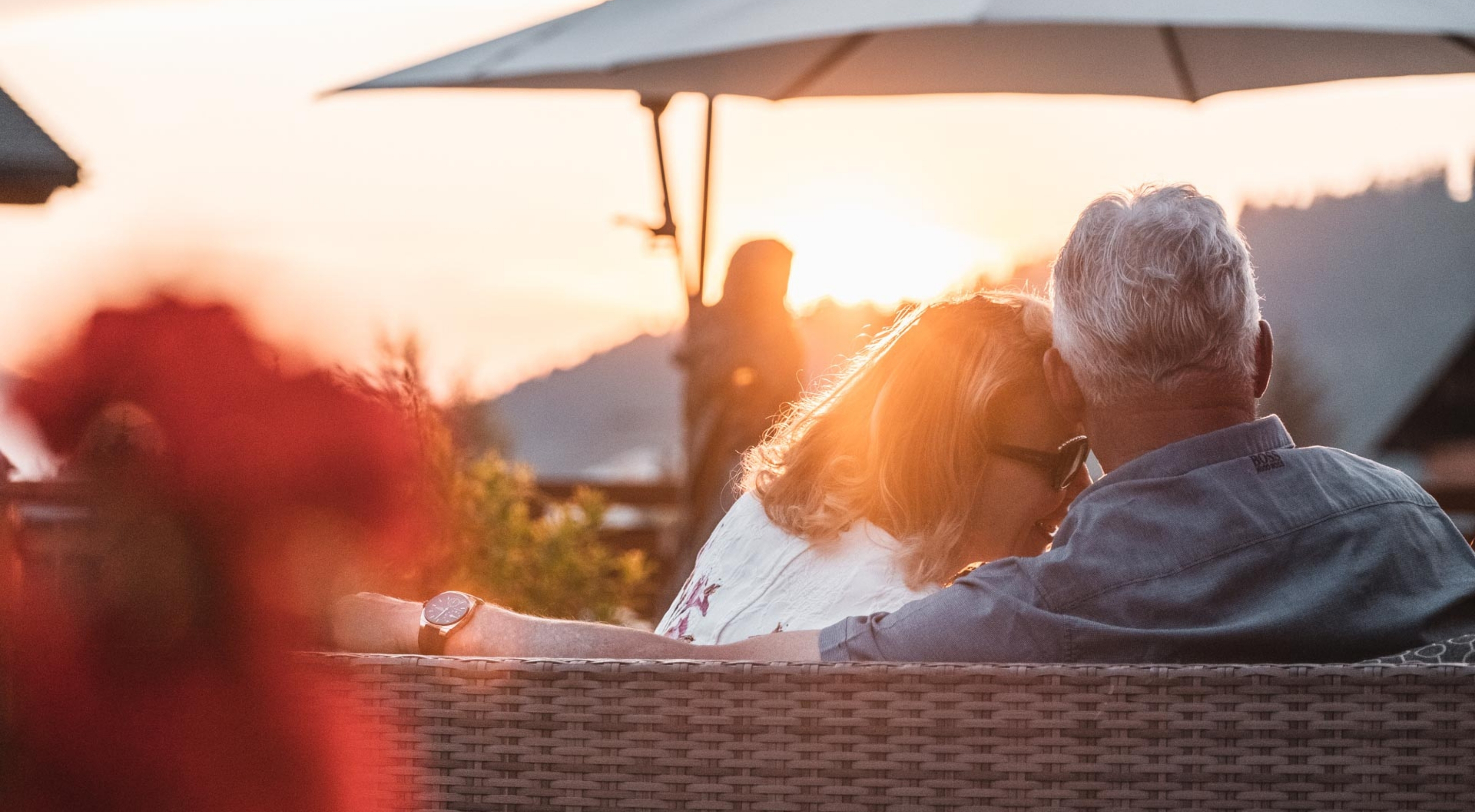 Photo of a couple sitting on a bench enjoying the view of the Alps